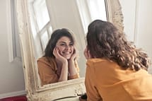 a smiling woman in front of a mirror
