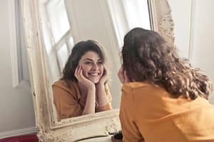 a smiling woman in front of a mirror